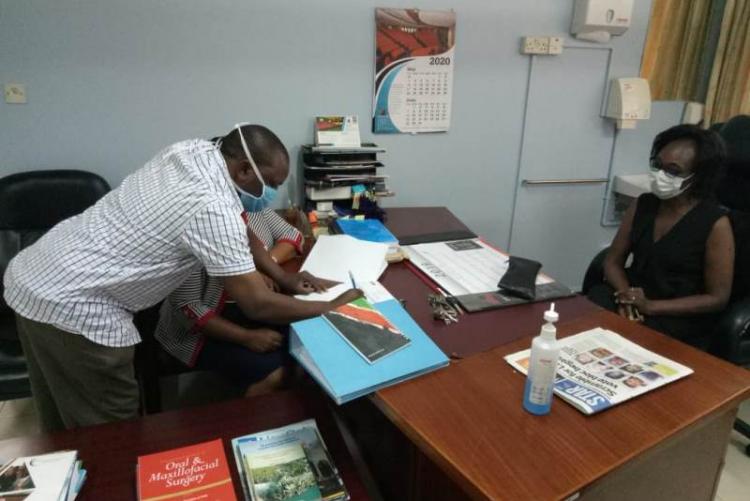 UHS Bursar Mr. Otiende signing and Looking on is outgoing CMO Dr. Asimba