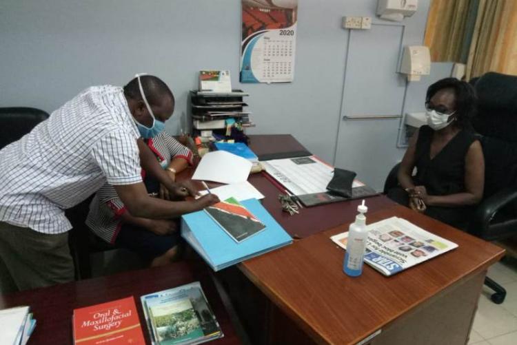 UHS Bursar Mr. Otiende signing and Looking on is outgoing CMO Dr. Asimba