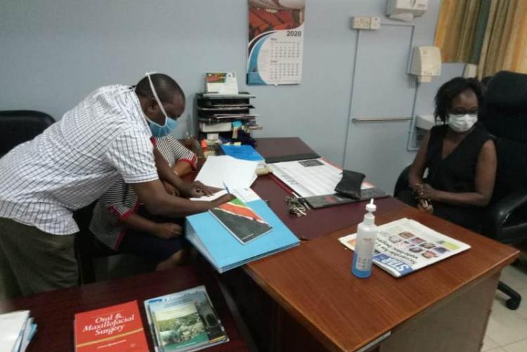 UHS Bursar Mr. Otiende signing and Looking on is outgoing CMO Dr. Asimba