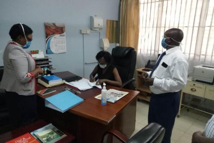 Former CMO Dr. Asimba signing handover notes witnessed by Incoming CMO Dr. Muhia and UHS Admin Mr. Kinyanki
